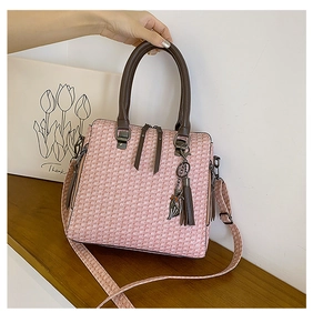 Detailed macro view of pink tweed woven texture with brown leather tassel and cat charm