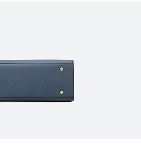 Detail view of lychee texture blue leather handbag base with gold protective studs