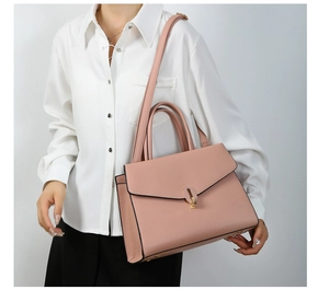 Pink lychee texture handbag with gold twist lock worn by a model in a minimal setting