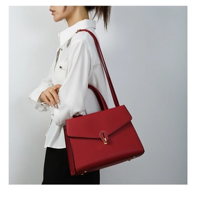 Side view of dark red shoulder bag with gold U-shaped lock on minimalist background