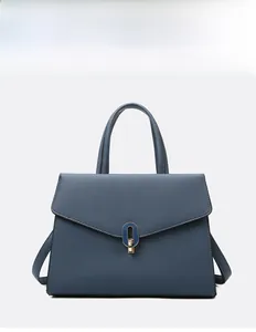 Close-up of matte blue leather handbag with elegant gold oval twist lock closure