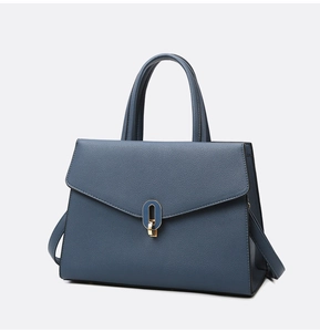 Detailed macro view of dark blue litchi grain leather bag with golden oval metal clasp