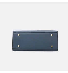 Detail view of the blue leather bag bottom featuring four golden metal protective studs