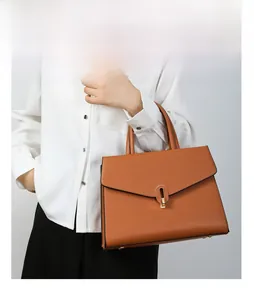 Detail of brown litchi pattern leather handbag featuring a golden oval metal lock