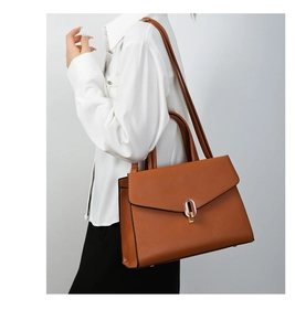 Close-up of caramel leather handbag featuring a silver oval metal buckle and fine texture