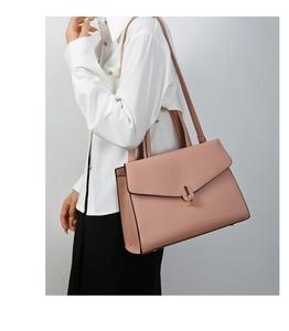 Close-up of pink pebbled leather bag with gold oval buckle and accordion side gusset