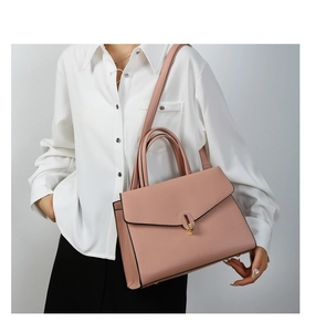 Dusty pink grained leather handbag with gold twist lock shown on model with white shirt