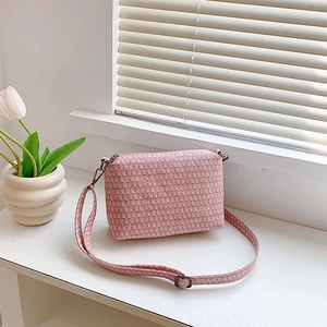 Pink woven texture crossbody bag with adjustable strap on a window sill with tulips