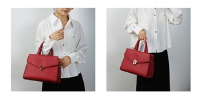 Detail view of red textured tote bag with golden oval clasp and sturdy top handles