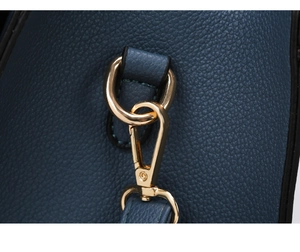 Detail of blue lychee grain leather handbag with shiny gold metal D-ring and lobster clasp