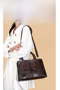 Detailed close-up of dark brown crocodile pattern embossed handbag with gold metal clasp