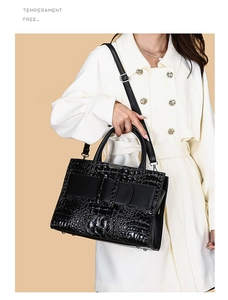 Detail of black crocodile pattern leather handbag with elegant decorative strap and handle