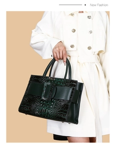 Close-up of dark green crocodile embossed handbag featuring a large square leather buckle