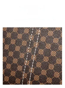 Macro detail of monogram patterned dark brown leather with durable white double stitching
