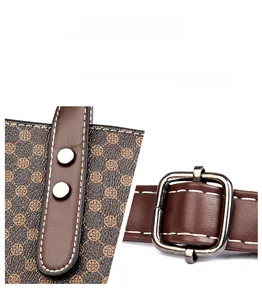 Detailed macro view of shiny metal hardware and textured monogram leather on a tote bag