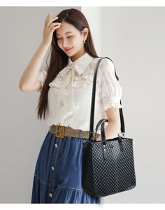 Detailed view of grey checkerboard tote bag with black leather handles and long shoulder strap