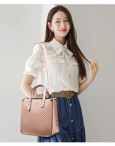 Detail of checkered tote bag with pink handles and black edge trim worn by a model