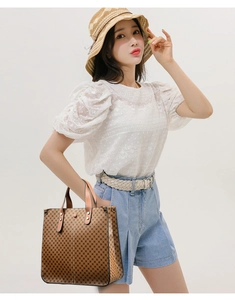 Close-up of a brown tote bag with geometric diamond texture held by a model