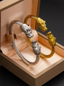 Détail de bracelets câble à double tête de lion en or et argent sur un écrin à bijoux