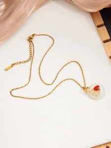 Détail macro du collier cygne doré avec pierre rubis et pendentif en jade blanc