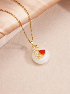 Gros plan du pendentif cygne doré avec pierre rouge et socle rond en imitation jade