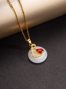 Détail d'un pendentif cygne doré avec pierre rouge et base en jade blanc sur fond en cuir noir