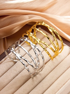 Détails de bracelets superposés irréguliers dorés et argentés sur tissu en soie
