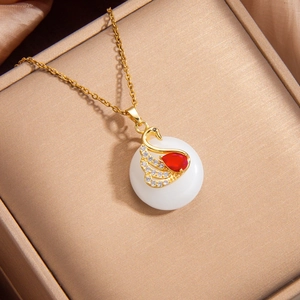 Collier cygne doré avec pierre blanche et cristal rouge dans un coffret à bijoux