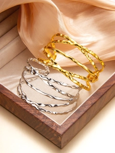 Détail de bracelets ouverts ondulés à plusieurs couches en or et argent à texture martelée