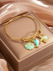 Detail of gold seashell starfish bracelet with mint enamel charms on satin background