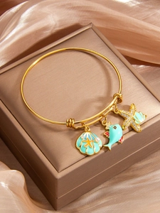 Detail view of gold ocean charms with blue shell, fish and starfish on silk
