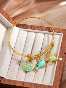Detailed shot of ocean-themed starfish and shell charms on adjustable gold bracelet
