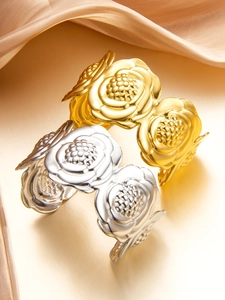 Dettaglio di bracciali a rosa oro e argento con petali stratificati su seta beige