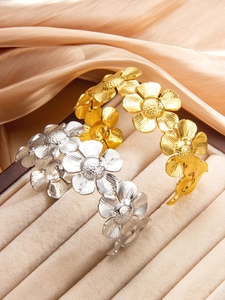 Vue détaillée des bracelets à fleurs dorés et argentés sur tissu en soie beige