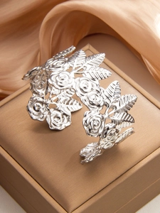 Detailed close-up of intricate rose relief and hollow engraving on silver wide cuff bracelet