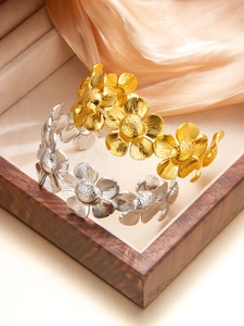 Détail de bracelets en forme de fleurs dorés et argentés sur fond de soie et velours