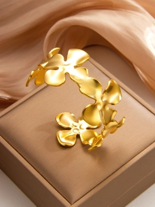 Vue détaillée du bracelet jonc trèfle plaqué or 18k sur de la soie élégante