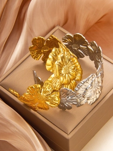 Detailed macro view of vintage gold and silver floral relief bracelets on silk