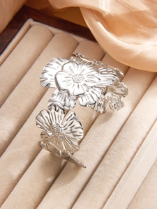 Detail of silver embossed floral cuff bangle with intricate petal textures on velvet