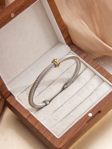 Detail of twisted cable bangle in silver and gold finish resting in a premium gift box