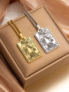 Detailed close-up of gold and silver tarot necklaces featuring The Tower card design