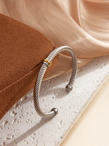 Detailed view of the twisted cable texture and gold-tone center ring on silver bracelet