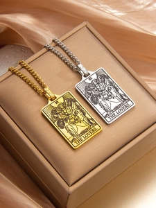 Close-up of gold and silver tarot card pendants on satin with The Lovers engraving