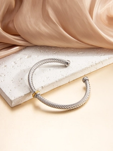 Close-up of twisted cable cuff bracelet with silver finish and gold-tone ball ends