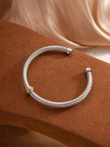 Detailed shot of twisted silver cable bracelet with gold accent on a display stand