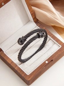 Detail of black punk skull bangle on silk inside a luxury wooden jewelry gift box