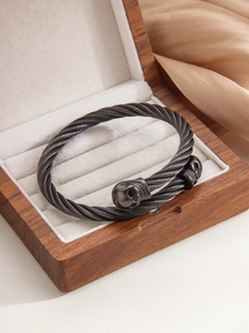 Macro shot of punk style gunmetal cable bangle featuring detailed twin skulls design