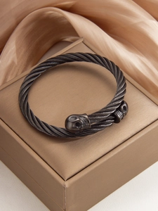 Macro shot of dark grey braided stainless steel bracelet with twin skull details