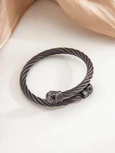 Macro detail of black cable texture and skull motif on the punk steel cuff bracelet
