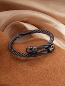 Detail of cable-twist punk skull bracelet in gun-grey steel on a premium display